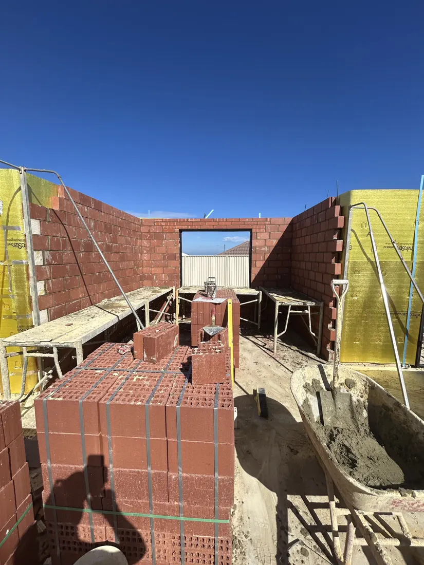 Red brick home build in progress with pallets